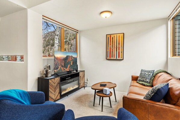 A modern living room with a fireplace, a large window with a mountain view, and a cozy seating area. - Experience luxury at Alpenglow at Telluride Lodge, a spacious 2 bed/2-bath condo (Telluride)