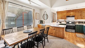 A modern kitchen with wooden cabinets, a central island, and a dining area with a wooden table and chairs. - Experience luxury at Alpenglow at Telluride Lodge, a spacious 2 bed/2-bath condo (Telluride)