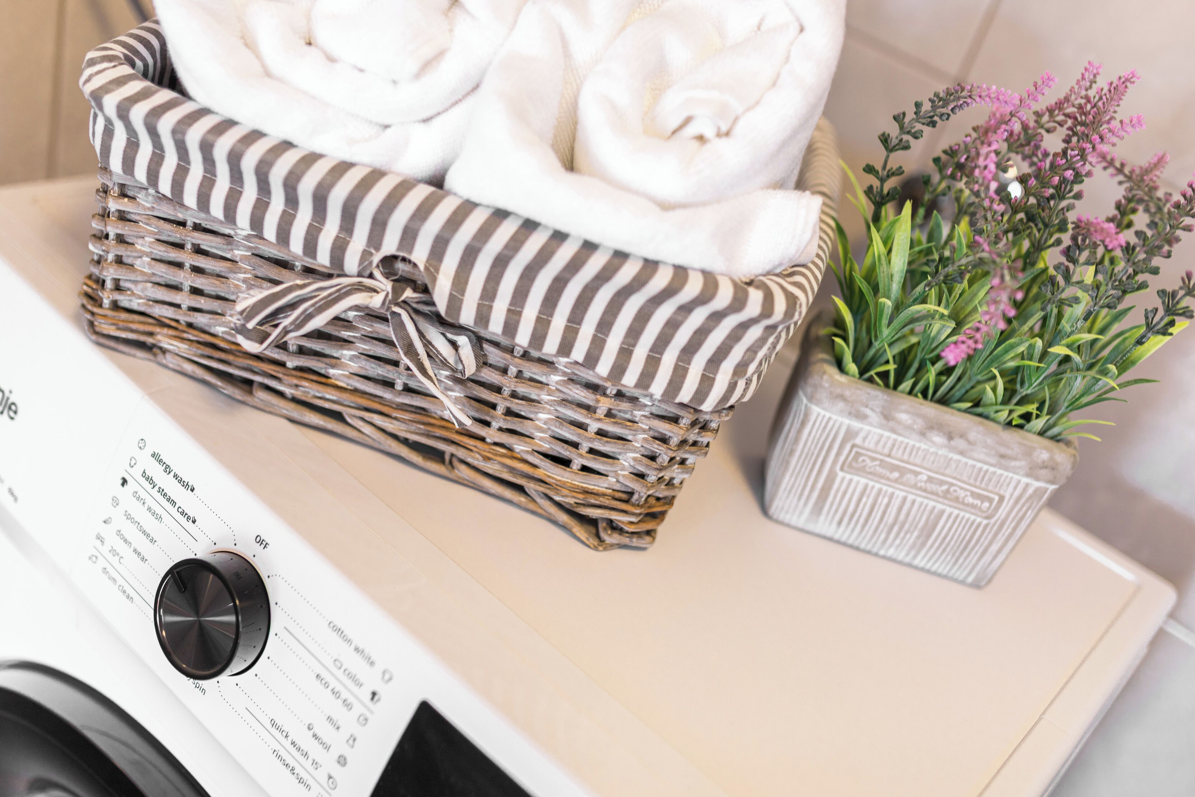 A laundry basket with folded towels, a potted plant, and a washing machine.