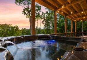 A hot tub area with a wooden deck and a view of trees.