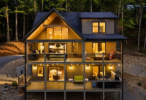 A two-story wooden cabin with a balcony, a deck, and a visible kitchen area.