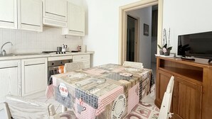 A compact kitchen with a dining table, a TV, and cabinets. - P062 - Porto Recanati, two-room apartment in the center 30 meters from the sea (Porto Recanati)