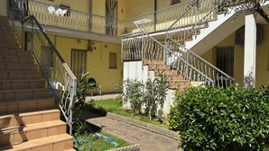 Ein mehrstöckiges Gebäude mit Außentreppe, Balkon und Garten.