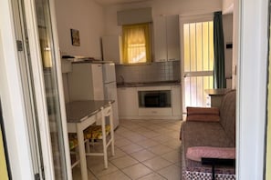 A compact kitchen with a dining area, a microwave, and a sofa. - CN012 – Cesenatico, One-Bedroom Apartment with Air Conditioning and Parking (Cesenatico)