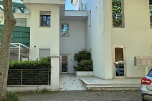 Un edificio residencial con entrada pavimentada, buzón y un coche estacionado afuera.