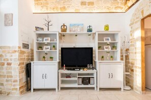 Una sala de estar con televisor de pantalla plana, gabinetes blancos y objetos decorativos.