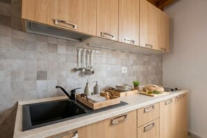 Una cocina con armarios de madera, un lavamanos negro y salpicadero de azulejos.