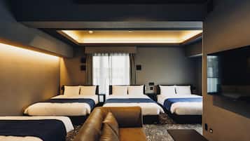A hotel room with three beds, a sofa, a flat-screen TV, and a large window with curtains.