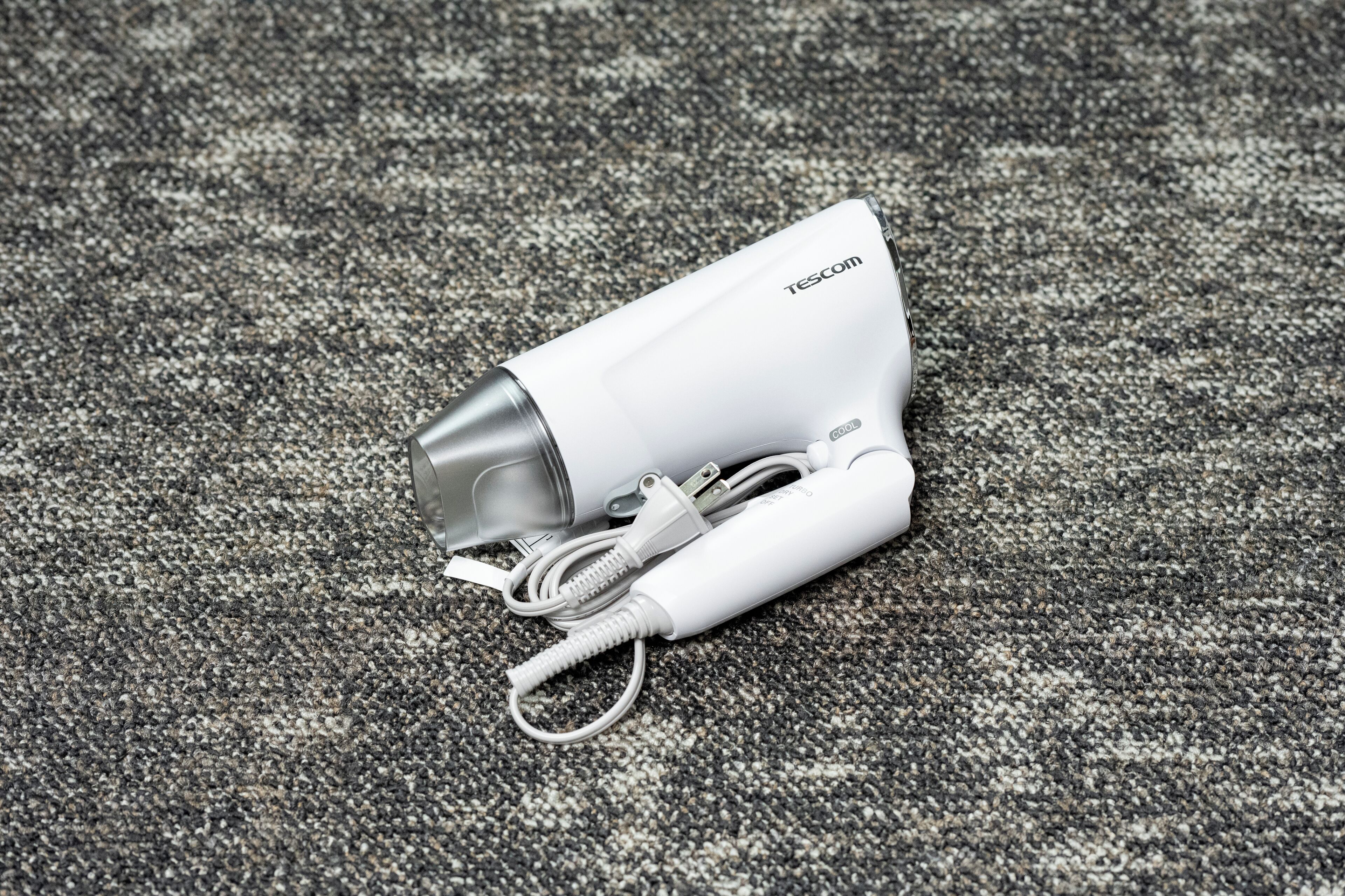 Un dispositivo blanco con un cable y un cordón enrollado, etiquetado como 