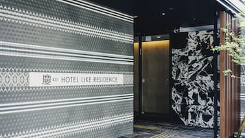 A hotel entrance with a patterned wall and a sign reading "HOTEL LIKE RESIDENCE."