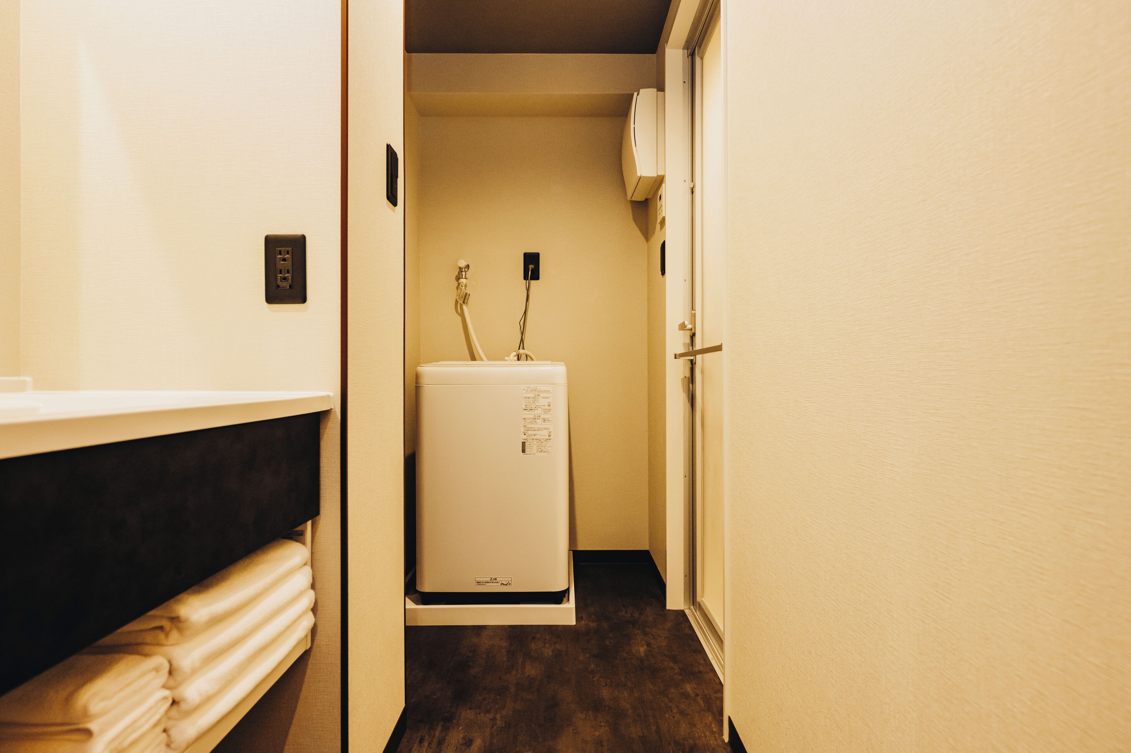 A narrow hallway with a white wall, a white door, and a white refrigerator in the center.