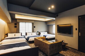 Ett hotellrum med två sängar, en soffa, en tv och en taklampa.