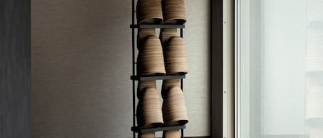 A tall, black, multi-tiered shoe rack against a textured wall by a window.