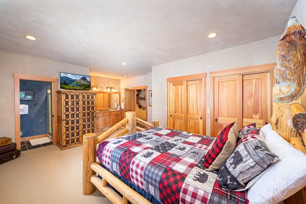 A bedroom with a wooden bed, a television, a wooden wardrobe, and a rustic decor theme.
