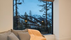 A cozy room with a large window overlooking a snowy mountain landscape.