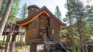 Una cabaña con un techo curvo distintivo, una escalera que lleva a la entrada y un letrero que dice "TAMARACK".