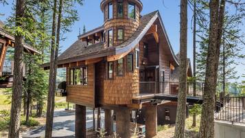 Une cabane en bois dotée d’une tour circulaire, de grandes fenêtres et d’un balcon.