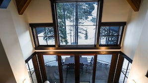 Una habitación con techos altos y ventanas amplias que muestran un paisaje nevado y árboles.