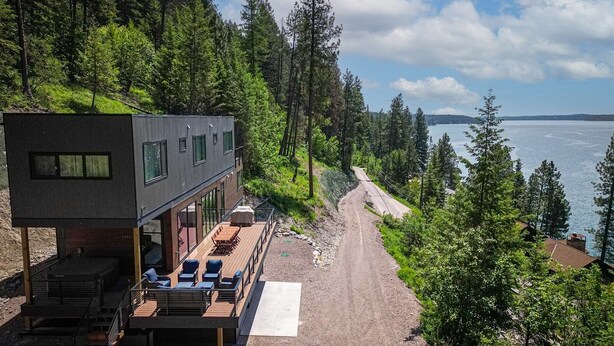 Een moderne chalet met terras, uitzicht op een bebost gebied en een waterpartij.