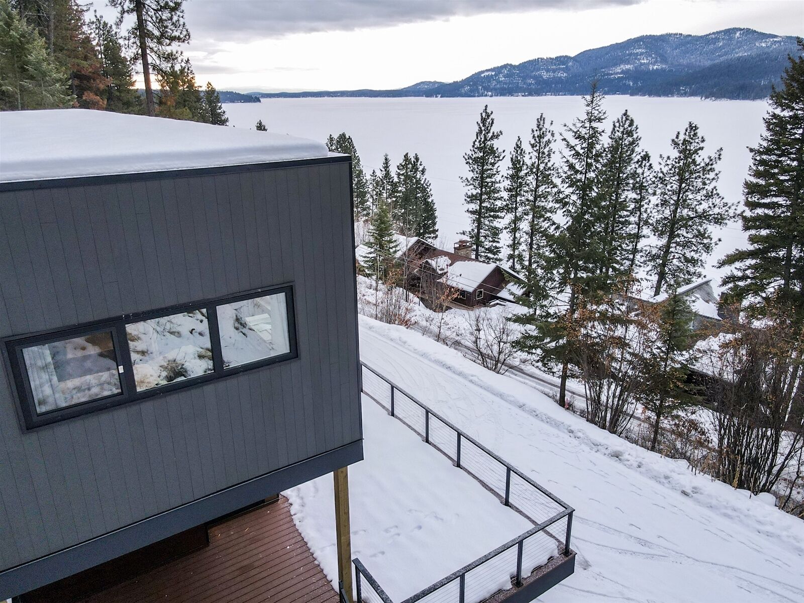 Un bâtiment moderne doté d’une grande fenêtre donnant sur un paysage enneigé et une étendue d’eau.