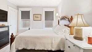 Un dormitorio con cama, lámpara de noche y cómoda.