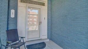 A blue brick exterior with a white door, a black chair, and a number '1' sign. - Evergreen Historic District 1928 Midtown Apartment (Memphis)