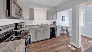 A modern kitchen with stainless steel appliances, grey cabinets, and a wooden floor. - Evergreen Historic District 1928 Midtown Apartment (Memphis)