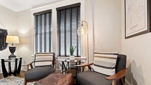 Un salon avec deux fauteuils, une table basse, une lampe et une carte accrochée au mur.