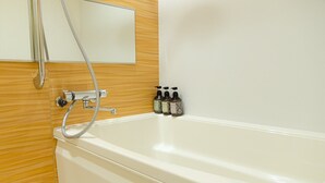 A white bathtub with a showerhead and two bottles of shampoo on the wall. - GRANDBASESUMIYOSHI (Fukuoka)