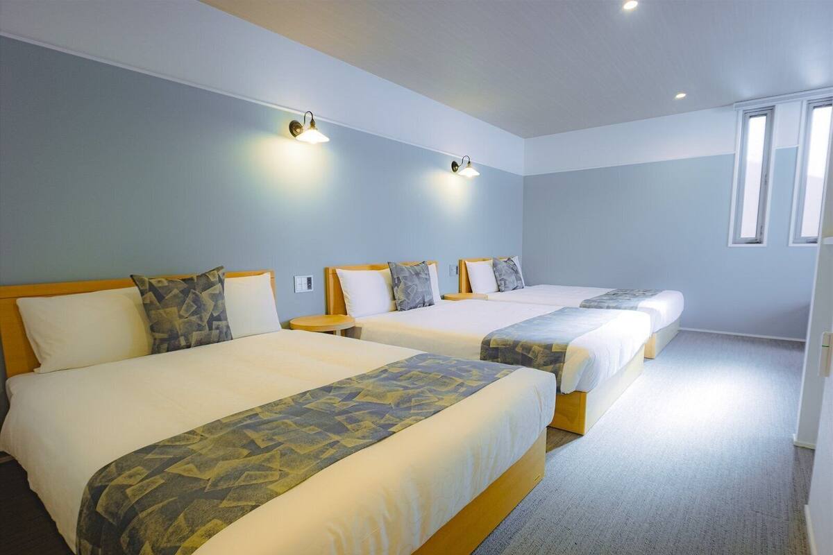Ett hotellrum med två sängar, ett litet bord och ett fönster.