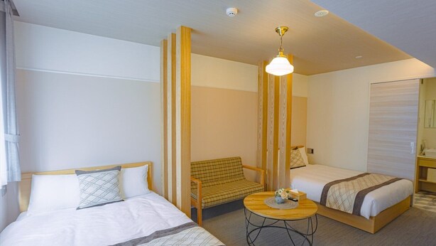 A hotel room with two beds, a small round table, a chair, and a canopy bed. - GRANDBASESUMIYOSHI (Fukuoka)