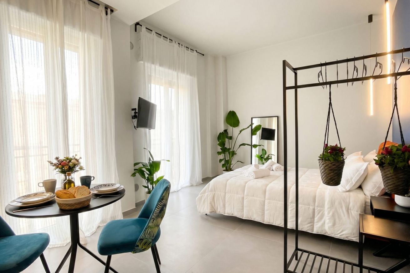 Una camera da letto moderna con un letto, una poltrona sospesa, un tavolo con articoli per la colazione e una TV.