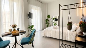 A modern bedroom with a bed, a hanging chair, a table with breakfast items, and a TV. - Floris - Sophisticated Studio (Bari)