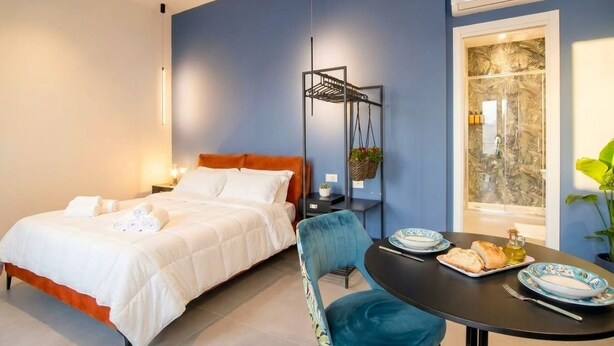 A bedroom with a bed, bedside table, and a window with a view. - Floris - Sophisticated Studio (Bari)