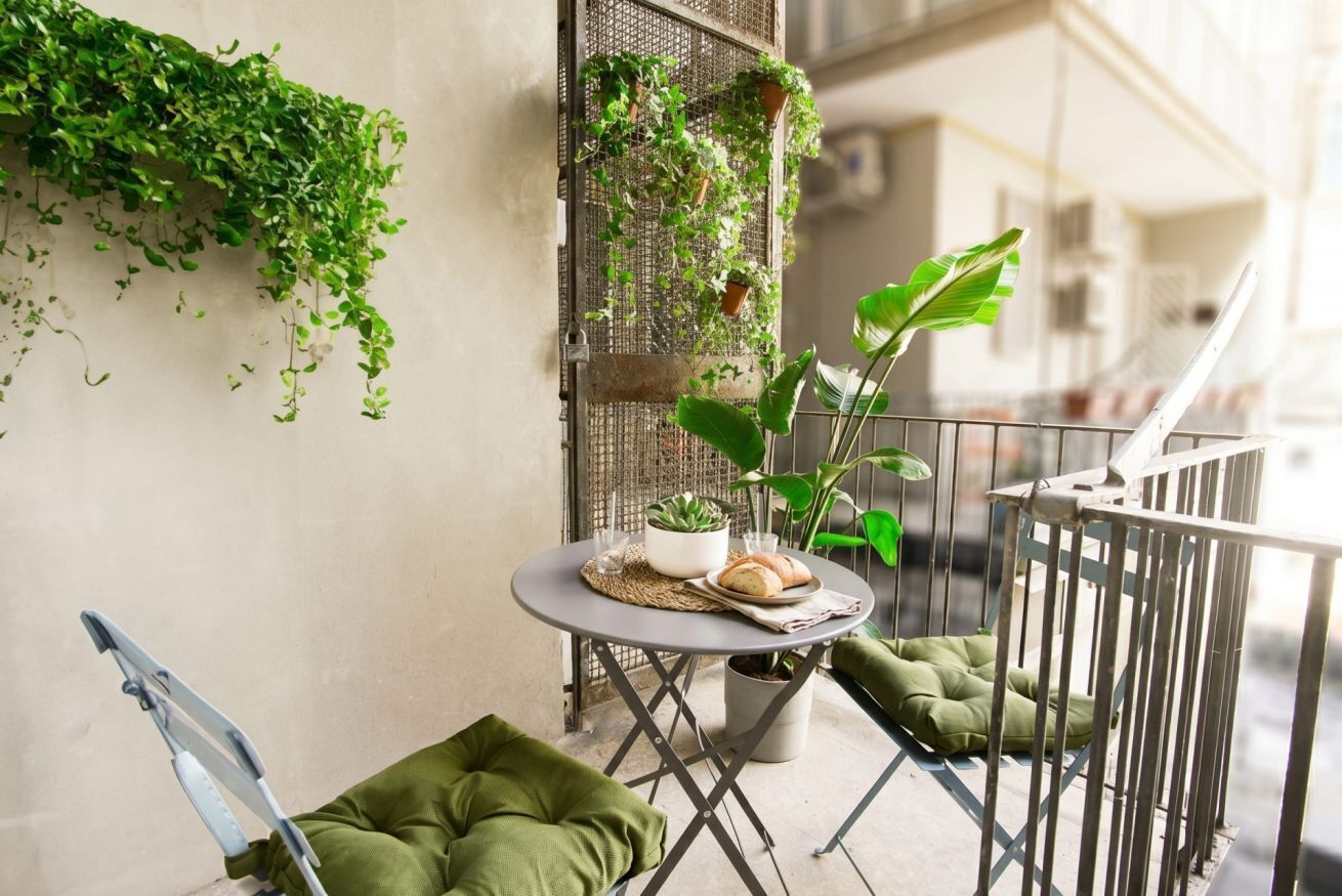 Un balcone con un tavolino, sedie e piante in vaso.