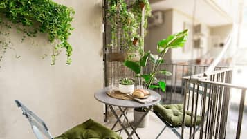 Un balcone con un tavolino, sedie e piante in vaso.