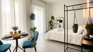 A modern bedroom with a bed, a hanging chair, a table with breakfast items, and a TV. - Floris - Sophisticated Studio (Bari)