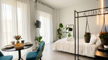 Una camera da letto moderna con un letto, una poltrona sospesa, un tavolo con articoli per la colazione e una TV.