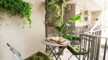 Un balcone con un tavolino, sedie e piante in vaso.