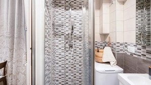 Ein modernes Badezimmer mit Glasdusche, gefliesten Wänden, Toilette und Waschbecken.