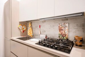 Une cuisine équipée d’une cuisinière à gaz, d’un évier et d’ustensiles de cuisine suspendus.