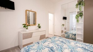Ein Schlafzimmer mit einem Bett, einem Schminktisch, einem Spiegel und einem Fernseher.