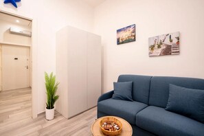 Uma sala de estar moderna com um sofá azul, um guarda-roupa branco e uma planta em vaso.