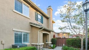 A two-story house with a beige exterior, a chimney, and a small front porch. - Spacious 4-bedroom townhome with Pool, WiFi, AC in marvelous Murrieta (Murrieta)