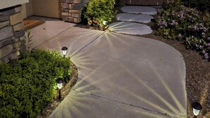 A well-lit pathway leading to a house with a stone and brick facade, a wooden gate, and a small garden area with shrubs and a flower bed. - Spacious 4-bedroom townhome with Pool, WiFi, AC in marvelous Murrieta (Murrieta)