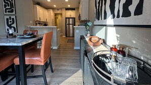 A modern kitchen with white cabinets, a central island, and a dining area with a table and chairs. - Spacious 4-bedroom townhome with Pool, WiFi, AC in marvelous Murrieta (Murrieta)