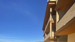 Un espace aménagé au bord de la piscine, avec une table et des chaises, un sol carrelé et une vue sur un paysage vallonné.