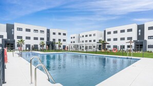 A modern hotel pool area with a clear blue pool, a lifeguard chair, and a palm tree. - Casa de los amigos Sea View Estepona (Málaga)
