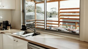 A modern kitchen with a large window, stainless steel sink, and wooden cabinets. - Sunset Hideaway - In Kingscote (Kingscote)