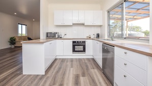 A modern kitchen with white cabinets, a built-in oven, and a dishwasher. - Sunset Hideaway - In Kingscote (Kingscote)